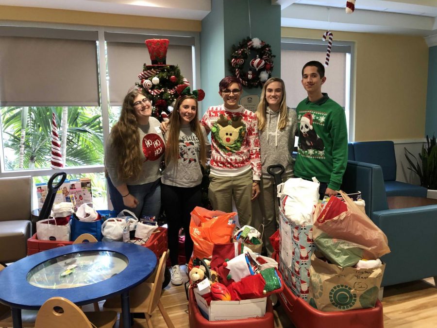 The NHS board members (left to right) Alexandra Garroway, Amanda Brennan, Michael McNeill, Christina Salsberry, and Braden Strackman stand behind the delivered stockings at The Childrens Hospital at Palms West.